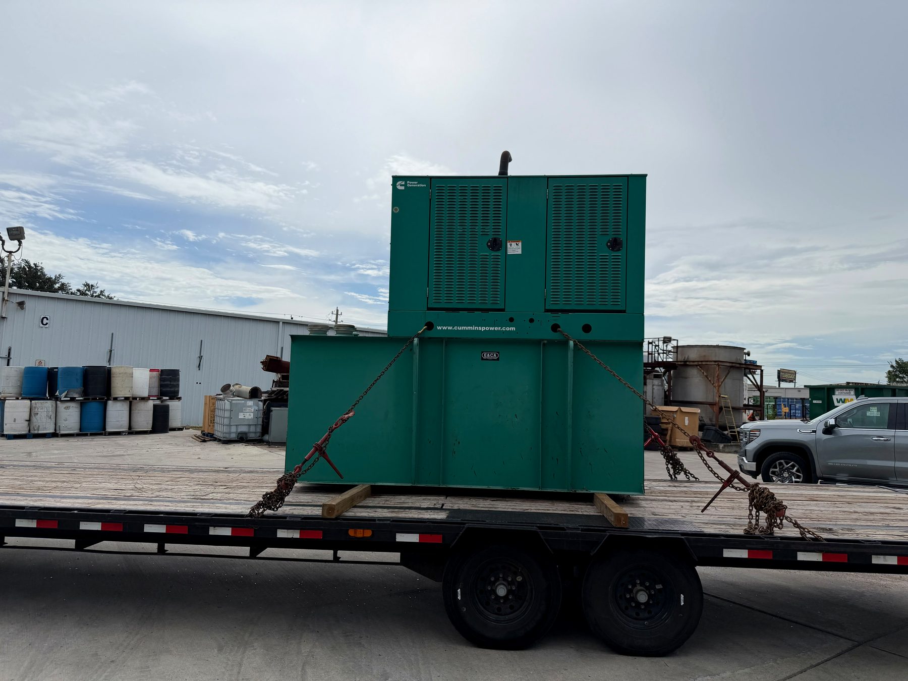 Cummins generator with sub-base fuel tank chained down on a flatbed trailer